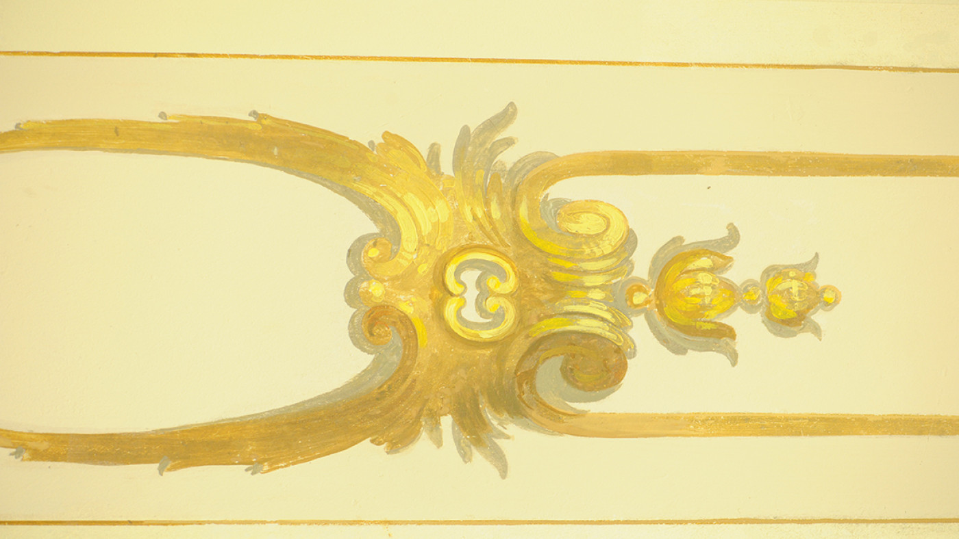 Restored ceiling ornament in gold and ochre tones on a cream ground.