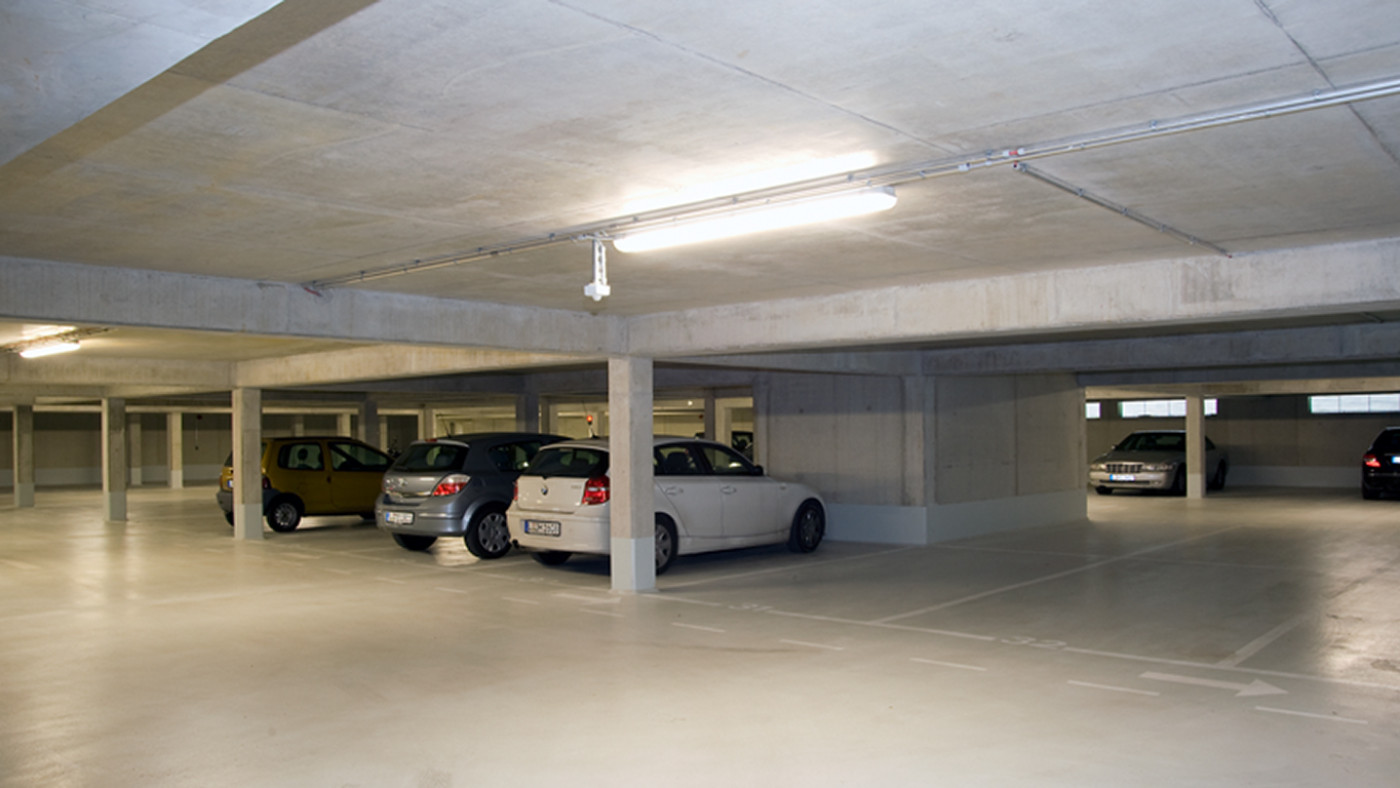 Underground car park with exposed concrete columns and parking spaces beneath the building.