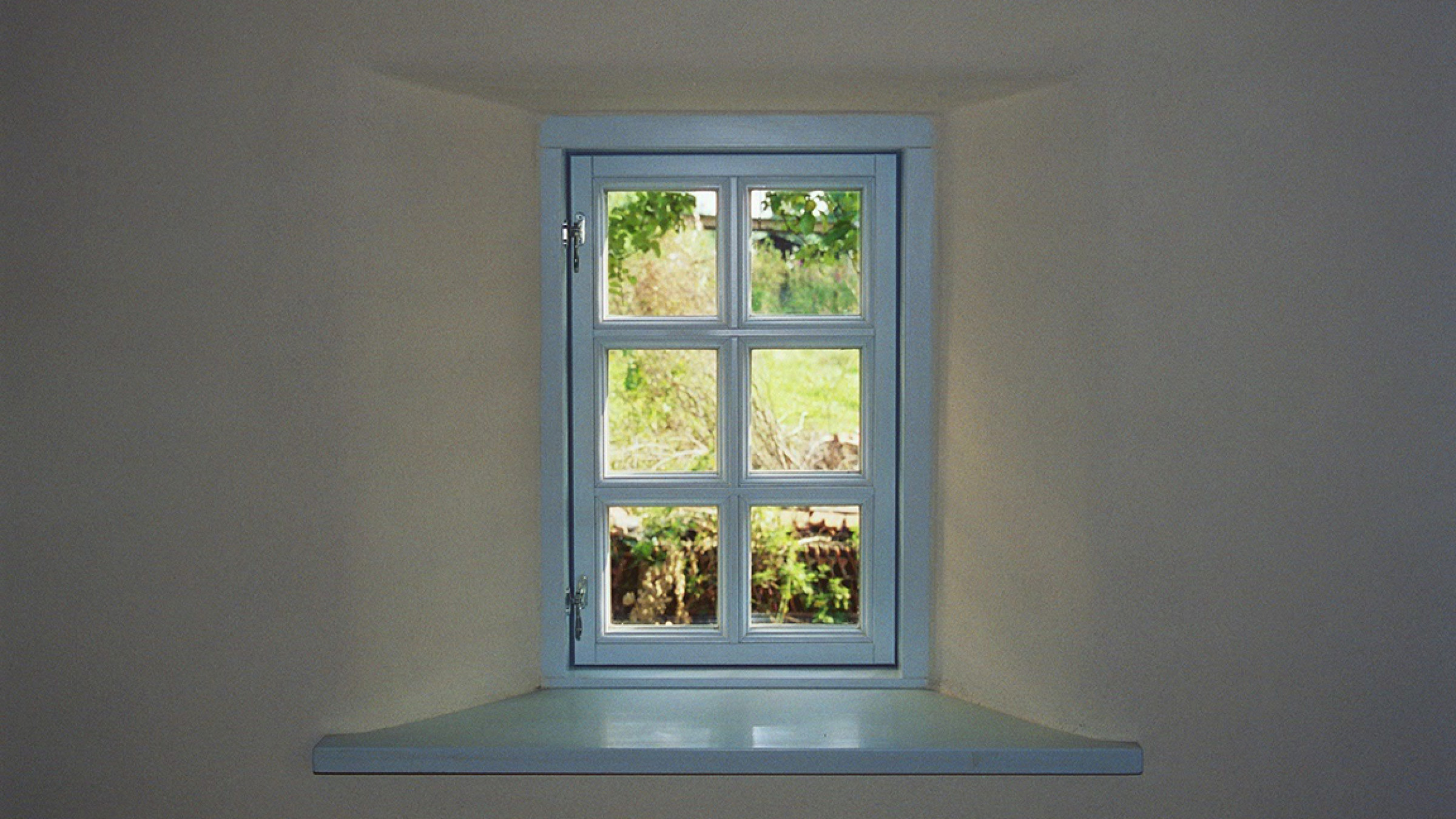 Deep white window reveal with a pale blue glazing-bar window and a view into the garden.
