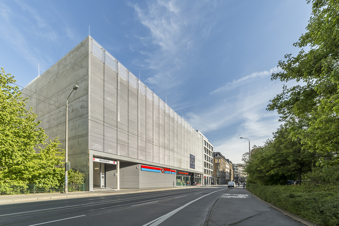 Multi-storey car park with an exposed concrete structure behind expanded metal cladding, the street in front.
