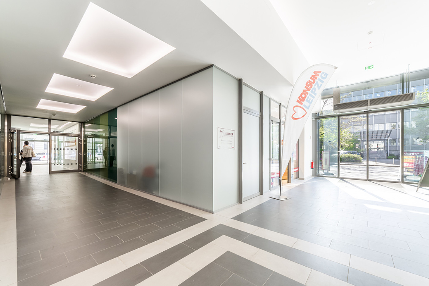 Passage with satin-finish glass, a seating corner by the window and a beach flag of the Leipzig Konsum co-operative.